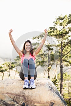 Young happy jogger sitting on rock cheering