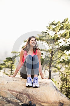 Young happy jogger sitting on rock looking away