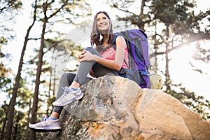 Young happy jogger sitting on rock and looking away