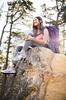 Young happy jogger sitting on rock and looking away