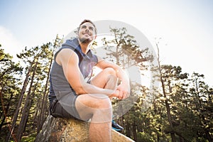 Young happy jogger sitting on rock and looking away