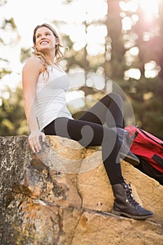 Young happy jogger sitting on rock and looking away