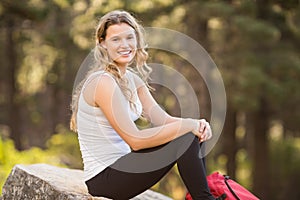 Young happy jogger sitting on rock and looking at camera