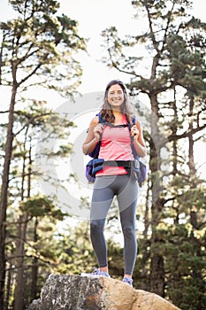 Young happy jogger standing on rock looking at camera