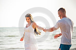 Young happy and joyful Caucasian adult romantic couple dancing on the tropical summer beach - honeymoon travel and leisure concept