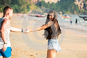 Young happy and joyful Caucasian adult romantic couple running and walking together while holding hands in summer wear on tropical
