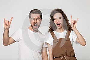 Young happy joyful couple raising hands with rock horns sign.
