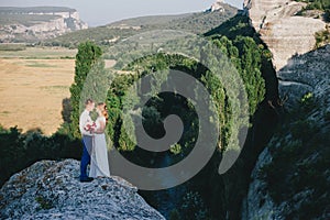 Young happy just married couple posing on the top of the mountain