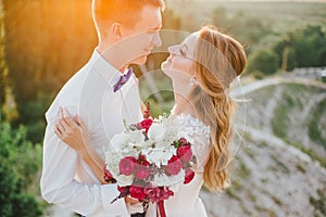 Young happy just married couple posing on the top of the mountain