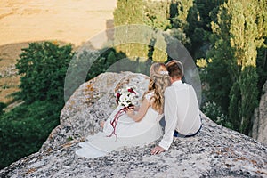 Young happy just married couple posing on the top of the mountain