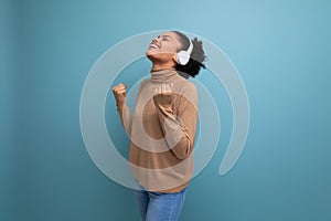 young happy latin female music lover with curly hair isolated studio background with copy space