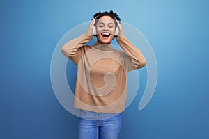 young happy latin female music lover with curly hair isolated studio background with copy space