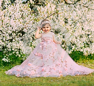 Young happy little girl fairy princess. Happy child face is smiling. Luxurious fluffy long dress for children, pink