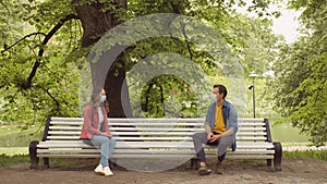 Young, happy, loving couple having date on the bench in the park During the coronavirus lockdown crisis. Relations