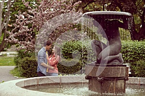 Young, happy, loving couple having date in the park near fountain. Relations, friendship and love.