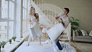 Young happy and loving couple having pillow fight in bed at home