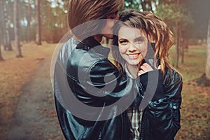 Young happy loving couple in leather jackets hugs outdoor on cozy walk in forest