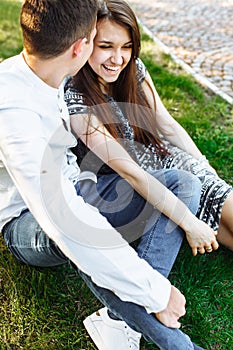 Young, happy, loving couple, sitting together on the grass in the Park, and enjoying each other, advertising, and inserting text