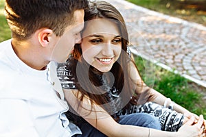 Young, happy, loving couple, sitting together on the grass in the Park, and enjoying each other, advertising, and inserting text