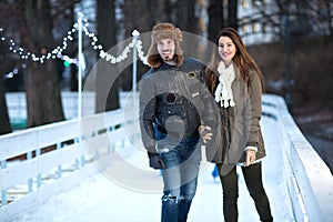 Young happy loving couple skating at ice rink outdoors