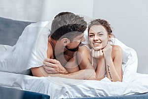 Young happy loving couple under blanket in bed