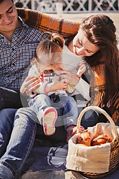 Young happy loving family with small child at picnic, enjoying time at beach sitting and hugging near ocean