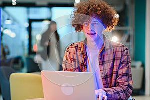 Young happy male freelancer in casual clothes sitting in cafe with laptop and using mobile phone.