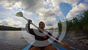Young happy man actively paddling kayak, singing. Action camera