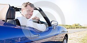 Young happy man in blue convertible car outdoors summer country side