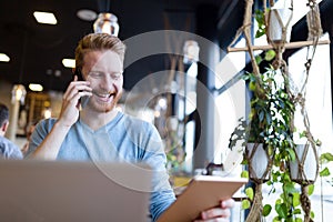 Young happy man having phone call in cafe