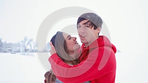 Young happy man hugging his girlfriend. Emotional couple in love hugging at winter on snow background.
