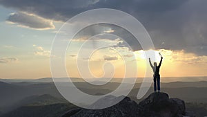 A young happy man joyfully raises his hands up to enjoy the sunset.