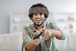 Young happy man laughing and playing video games on weekend