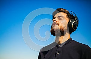 The young happy man listen to the music from the headphones