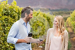 Young happy man offering wine to a young woman