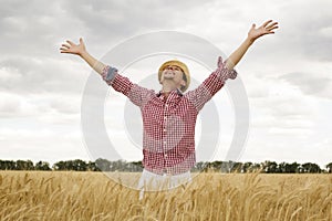 Young happy man with outstretched arms in a wheat field. Concept of freedom