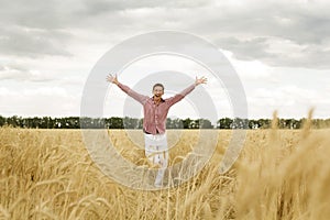 Young happy man with outstretched arms in a wheat field. Concept of freedom