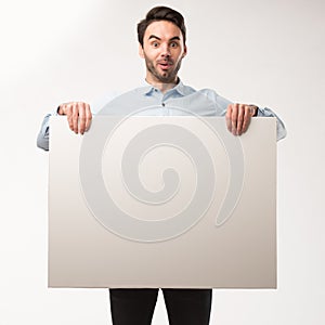 Young happy man showing presentation, pointing on placard over gray background