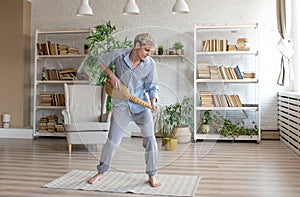 a young happy man sings and dances with a broom for cleaning in a large room.