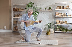 a young happy man sings and dances with a broom for cleaning in a large room.