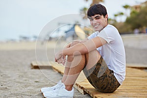 Young happy man sitting on beach smiling