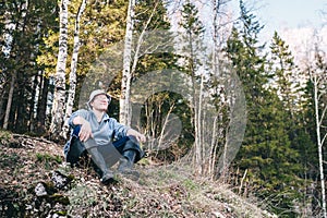 Young happy man sitting and relaxing near forest, countryside