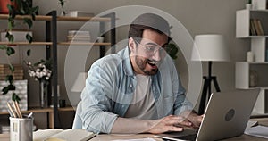 Young happy man using laptop receive notification with great news