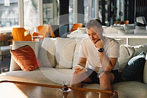 Young happy man using mobile phone in hotel lobby.