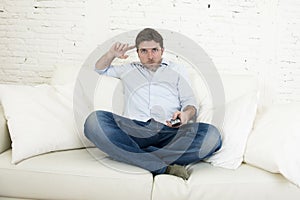 Young happy man watching television in disbelief and shock face expression