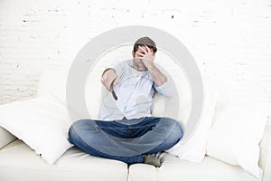 Young happy man watching television horror movie covering his eyes scared and horrified