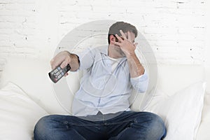 Young happy man watching television horror movie covering his eyes scared and horrified