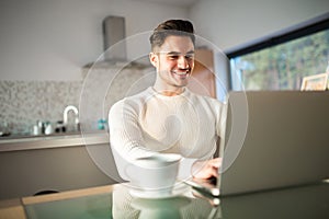 Young happy man working at home on laptop