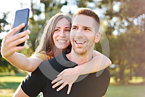 Young happy millennial couple smiling and taking selfie - Z generation tourists having fun together - Technology concept with a