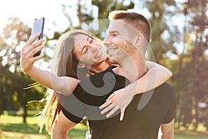 Young happy millennial couple smiling and taking selfie - Z generation tourists having fun together - Technology concept with a